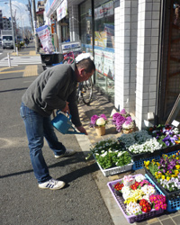 画像：店先の花に水をやっているのは息子さんだ