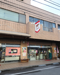 画像：よみせ通りの中ほどに位置するコシヅカハム。この旗が目印だ